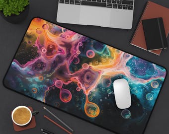 Op de afbeelding: Een grote, rechthoekige bureaumat met een levendig, abstract ontwerp in tinten oranje, roze, paars en blauw. De mat heeft een zwarte rand en is omgeven door een laptop, muis en andere kantoorbenodigdheden.