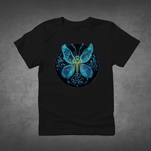 Könnte beinhalten: Schwarzes T-Shirt mit einem kreisförmigen Design, das einen blauen Schmetterling zeigt. Der Schmetterling hat detaillierte Flügel und einen gelben Körper. Das Design ist vor einem dunklen Hintergrund platziert.