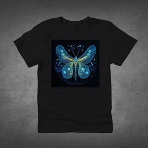 Könnte beinhalten: Schwarzes T-Shirt mit einem detaillierten Schmetterlingsdesign. Der Schmetterling hat blaue und gelbe Flügel mit einem Punktmuster, vor einem schwarzen Hintergrund. Das Design ist auf dem T-Shirt zentriert und erzeugt einen auffälligen visuellen Effekt.