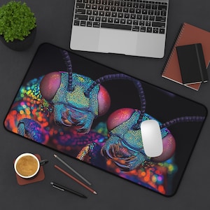 May include: A black rectangular mousepad featuring a macro image of two iridescent insect heads with large, red eyes. The insect heads are detailed with blue, green, and purple hues. A white mouse and a laptop are also visible.