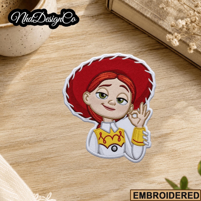 May include: Embroidered patch featuring a cartoon character with red hair, a red hat, and a white shirt with a yellow collar. The character is giving an "okay" hand gesture. The patch has a white border.