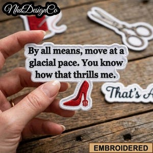 May include: Embroidered patch with the text "By all means, move at a glacial pace. You know how that thrills me." and a red high heel design. The patch is white with black text and a red heel.