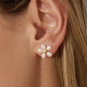 May include: A pair of delicate flower-shaped earrings with white pearls and a small gold accent in the center.