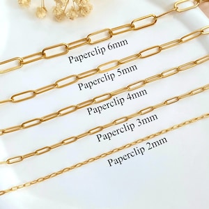 Puede incluir: Cinco cadenas doradas tipo clip de papel de diferentes anchos dispuestas horizontalmente. Las etiquetas de texto indican anchos de 6mm, 5mm, 4mm, 3mm y 2mm. Cada cadena presenta eslabones rectangulares alargados en un patrón uniforme.