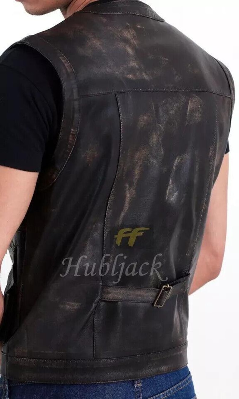 May include: A distressed black leather vest with a buckle closure. The vest has a worn, vintage appearance with visible texture and subtle color variations. The text "FF Hubljack" is printed on the lower back.