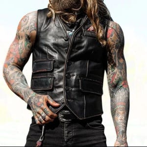 Peut inclure: Un gilet en cuir noir avec un devant &agrave; boutons et plusieurs poches. Le gilet a des d&eacute;tails de couture blanche autour des bords et des poches.