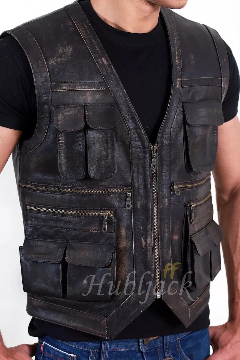 May include: A distressed black leather vest with multiple pockets and a front zipper closure. The vest has a worn, vintage appearance, with visible wear and tear. The text "Hubljack" is visible on the lower right side of the vest.