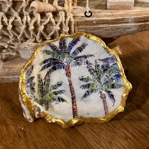 Könnte beinhalten: Eine weiße Austernschalen mit goldenem Rand, verziert mit einem farbenfrohen Palmenbaum-Design. Die Schale ist ein dekoratives Schmuckstück oder eine Schale.