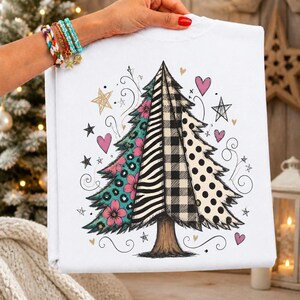 May include: A white t-shirt featuring a graphic of a Christmas tree divided into four vertical sections with distinct patterns: teal leopard print with pink flowers, black and white zebra stripes, black and white buffalo plaid, and white with black polka dots.