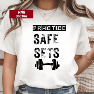 Könnte beinhalten: Weißes T-Shirt mit dem Text "PRACTICE SAFE SETS" in schwarzer, verwaschener Schrift. Unter dem Text befindet sich eine schwarze Hantel-Grafik. Das Shirt hat kurze Ärmel und einen Rundhalsausschnitt.