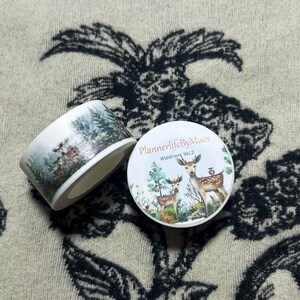 Op de afbeelding: Een rol washi tape met een boslandschap met herten, een vogel en bomen. De tape is gelabeld "PlannerlifeByMues" en "Wildtiere Vol. 2".