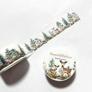 Op de afbeelding: Een rol washi tape met een witte achtergrond en een herhalend patroon van bossc&egrave;nes met herten, bomen en vogels. De tape is gelabeld "PlannerlifeByMues Waldtiere Vol. 2".