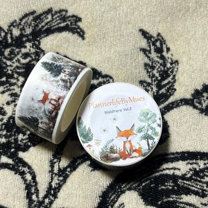 Op de afbeelding: Twee rollen washi tape met afbeeldingen van bosdieren. De eerste rol heeft een witte achtergrond met een besneeuwde bos sc&egrave;ne en een vos. De tweede rol heeft een witte achtergrond met een vos die in een bos zit met groene bomen en paddenstoelen. De tekst op de tweede rol is "PlannerlifeByMues Waldtiere Vol.2".