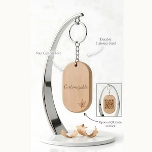 May include: A wooden, customizable keychain with a cannabis leaf design. The keychain hangs from a silver metal stand. The text "Customizable" is on the front. The back has an optional QR code. The stand is labeled "Durable Stainless Steel."