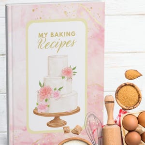 May include: A recipe book titled "My Baking Recipes" with a watercolour illustration of a three-tiered cake decorated with pink flowers. Baking ingredients and tools, including eggs, flour, and a rolling pin, are arranged around the book.