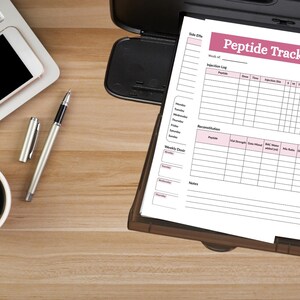 Puede incluir: Un documento impreso Peptide Tracker con un encabezado rosa, un registro de inyecciones, una tabla de reconstituci&oacute;n y una secci&oacute;n de dosis semanal. El documento descansa en una bandeja de impresora negra junto a una computadora port&aacute;til, un bol&iacute;grafo plateado y una taza de caf&eacute; negro.
