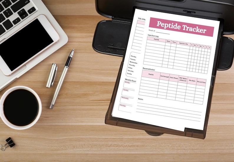 Puede incluir: Un documento impreso Peptide Tracker con un encabezado rosa, un registro de inyecciones, una tabla de reconstituci&oacute;n y una secci&oacute;n de dosis semanal. El documento descansa en una bandeja de impresora negra junto a una computadora port&aacute;til, un bol&iacute;grafo plateado y una taza de caf&eacute; negro.