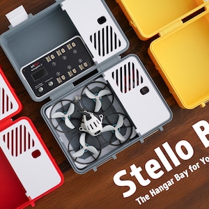 Könnte beinhalten: Ein graues, weißes und rotes Kunststoff-Aufbewahrungskoffer mit einer Drohne im Inneren. Der Koffer verfügt über eine eingebaute Ladestation und ein Etikett mit der Aufschrift "Stellio The Hangar Bay for Your Tinywhoop".