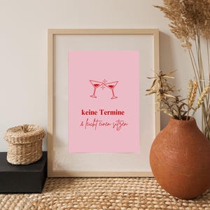 May include: A pink printable wall art design with a red outline of two martini glasses clinking. The text reads "keine Termine & leicht einen sitzen".