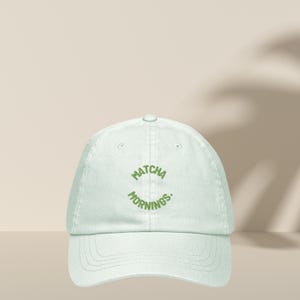 Peut inclure: Une casquette de baseball vert clair avec le texte "MATCHA MORNINGS." brodé en vert sur le devant.