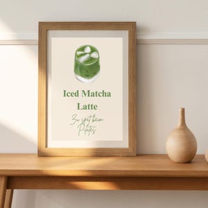 Könnte beinhalten: Ein gerahmter Druck mit einer grünen Illustration eines Eiskaffees mit Matcha. Der Text lautet "Iced Matcha Latte" und "3w spät beim Pilates."