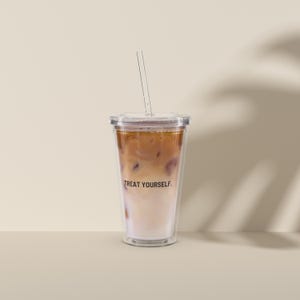 Könnte beinhalten: Ein durchsichtiger Plastikbecher mit Deckel und Strohhalm, gefüllt mit Eiskaffee. Auf dem Becher steht der Text "TREAT YOURSELF."