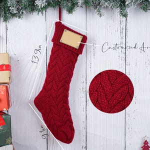 May include: A red knitted Christmas stocking, 13.9 inches long and 9.1 inches wide, with a customizable area. The stocking is hanging against a white wooden background with Christmas decorations.