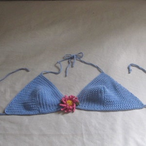 May include: A light blue crocheted bikini top with a pink flower embellishment.