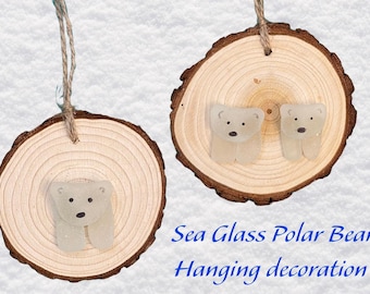 May include: Two wooden ornaments with hanging twine, each featuring a sea glass polar bear. The ornament on the left has one bear, while the ornament on the right has two bears. The text "Sea Glass Polar Bear Hanging decoration" is below the ornaments.