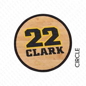 May include: A circular patch with a basketball court design. The number "22" is in black with a yellow outline, above the name "CLARK" in black. The patch has a black border and the word "CIRCLE" is printed vertically on the right.