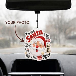 May include: A hanging car air freshener featuring a cartoon Santa Claus illustration with the text I'm not SANTA I'm the CEO of HO HO HO! Elf Union? I don't know him. NORTH POLE, BIG BOSS! The design includes a space for a custom photo.