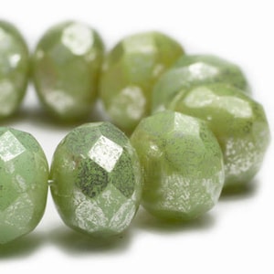 May include: A strand of green glass beads with a silver metallic finish. The beads are faceted and have a slightly irregular shape.