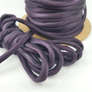 May include: A spool of dark purple satin cord. The cord is soft and smooth, and it is ideal for crafting or decorating.