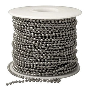 Op de afbeelding: Een spoel met zilveren ballenketting. De ketting is om een witte kunststof spoel gewikkeld. De ketting is gemaakt van kleine, ronde metalen ballen.