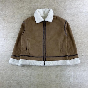 Può includere: Giacca in camoscio marrone con colletto e finiture in montone bianco. La giacca ha una cerniera a tutta lunghezza e due tasche anteriori. I polsini e l'orlo sono rifiniti con montone bianco. La giacca è lunga circa 71 cm.