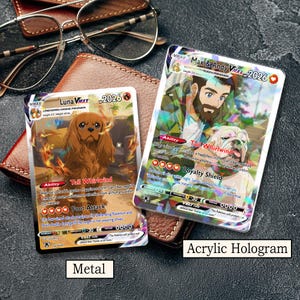 May include: Two rectangular trading cards featuring custom illustrations. The left card, labeled Metal, depicts a brown Cavalier King Charles Spaniel. The right card, labeled Acrylic Hologram, shows a person with a beard and a bulldog. Both cards display text including Max & Andy VMAX, Luna VMAX, and various game statistics.