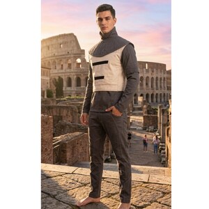 May include: A person wearing a grey long-sleeved shirt, matching trousers, and a beige vest with black accents. The vest has a high collar and two horizontal black stripes. The background features the Colosseum and a sunset.