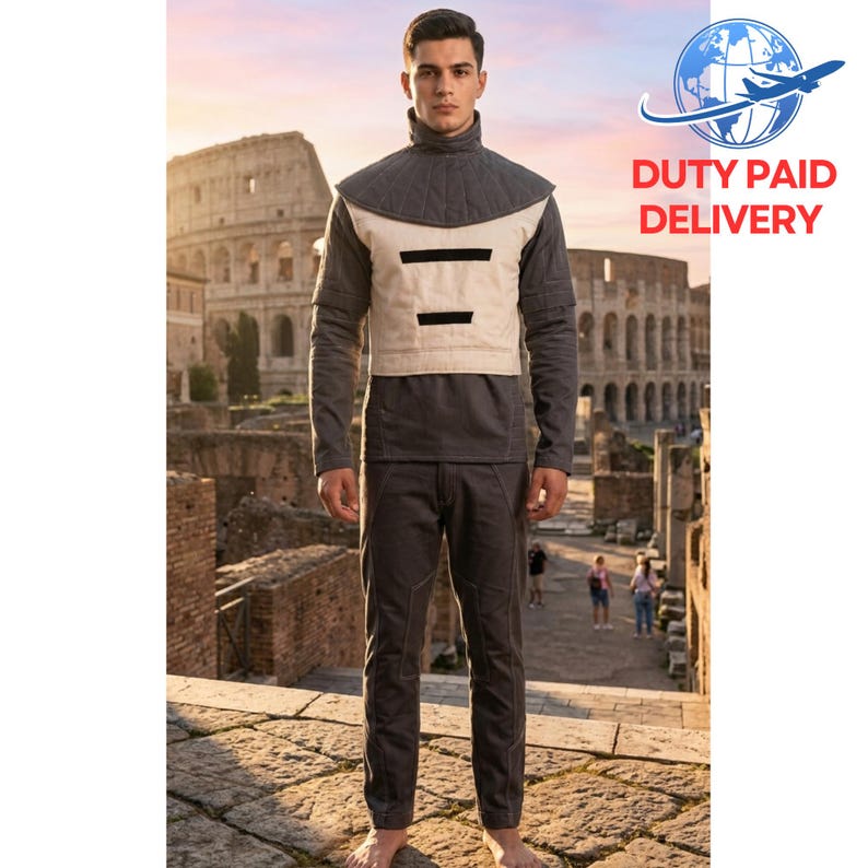 May include: A person wearing a grey and beige outfit with a high collar, standing in front of the Colosseum. The outfit includes a long-sleeved shirt, a vest with black accents, and matching trousers. The background features the ancient Roman amphitheatre.