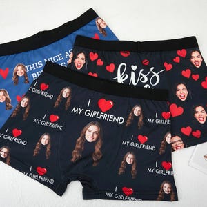 May include: Three pairs of boxer briefs with custom photo prints. One pair is blue with faces and hearts, another is black with faces, hearts, and the word "kiss", and the third is black with "I ❤️ MY GIRLFRIEND".