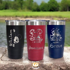 May include: Three stainless steel tumblers with personalised engravings. The black tumbler features Mickey Mouse peeking around the corner with the name "William". The red tumbler has a Disney castle and fireworks with the text "Disney 2025" and the name "Johnson". The blue tumbler has a cruise ship with the text "Let's Cruise" and the name "Steve".