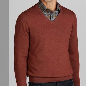 May include: A rust-colored v-neck sweater with long sleeves. The sweater is made of a soft, knit fabric.