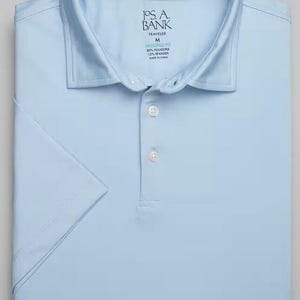 May include: A light blue short-sleeved polo shirt with a button-down collar. The shirt has a label that reads "JOS. A. BANK TRAVELER M TAILORED FIT 85% POLYESTER 15% SPANDEX MADE IN CHINA."