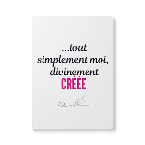Peut inclure: Un carnet blanc avec le texte noir "...tout simplement moi, divinement" suivi du mot "CRÉÉE" en rose. Sous le texte se trouve un dessin au trait noir représentant une main tenant un stylo et dessinant un petit cœur.