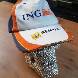 Può includere: Una tazza di ceramica bianca con manico nero e la scritta "But First, Coffee" in grassetto nero. La tazza è posta su uno sfondo sfocato. La tazza misura circa 10 cm di altezza.