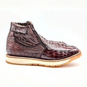May include: Brown leather boots with a zipper on the side. The boots have a textured pattern and a white rubber sole.