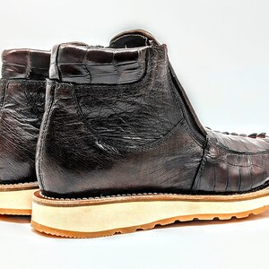 May include: A pair of brown leather ankle boots with a zipper on the side. The boots have a textured leather upper and a white rubber sole.