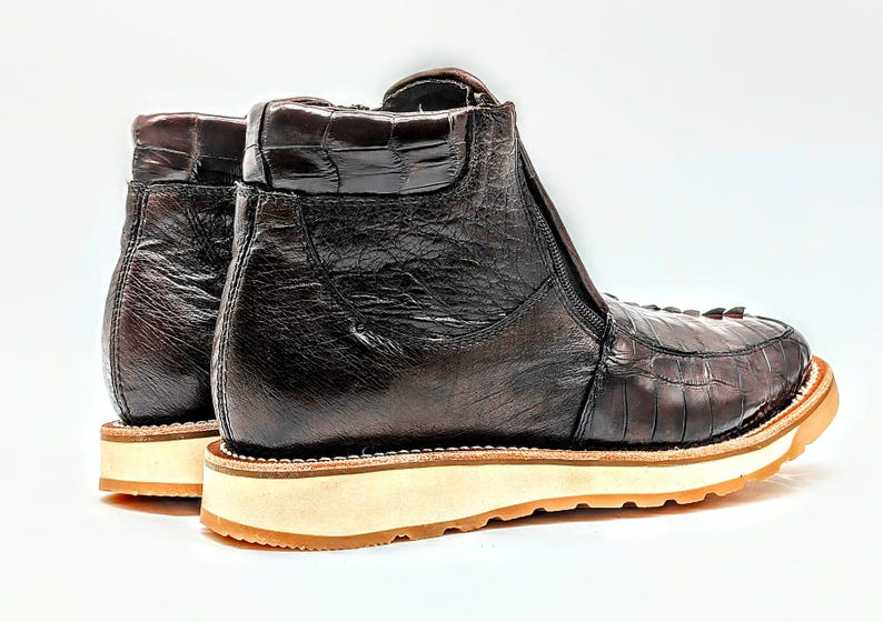 May include: A pair of brown leather ankle boots with a zipper on the side. The boots have a textured leather upper and a white rubber sole.