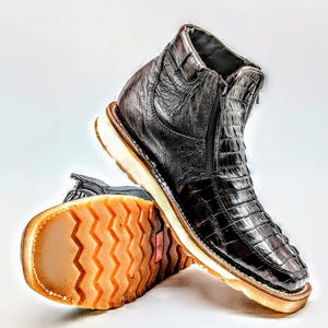 May include: A pair of brown leather boots with a zipper on the side. The boots have a textured sole and a white rubber outsole.