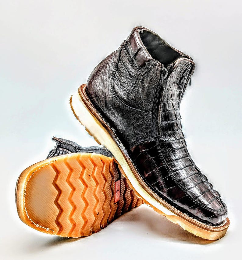 May include: A pair of brown leather boots with a zipper on the side. The boots have a textured sole and a white rubber outsole.