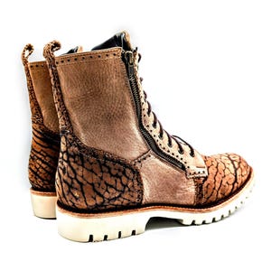 May include: Brown leather combat boots with a textured design and a side zipper. The boots have a white sole and brown laces. The heel is approximately 1.5 inches high.